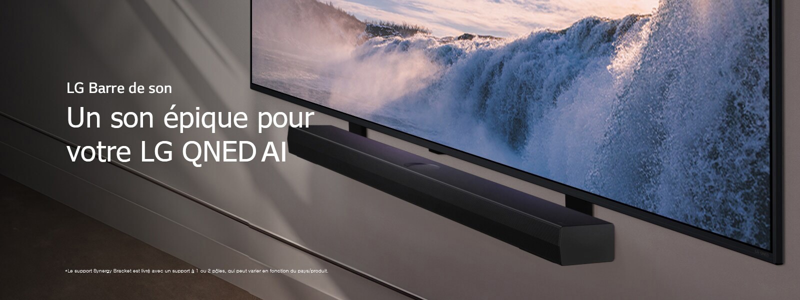 Vue inclinée en perspective d’un LG TV et d’une Soundbar montés sur un mur. La TV affiche un gros plan d’une cascade imposante, alors que la lumière du soleil illumine le mur, la TV et la Soundbar. Une notice indique : « Le support Synergy Bracket est livré avec un support à 1 ou 2 pôles, qui peut varier en fonction du pays/produit. »