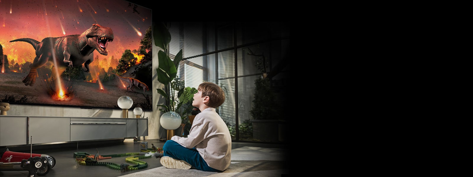 Une image d'un petit garçon assis par terre devant le LG OLED G2 de 97 pouces. Il regarde avec admiration un film de dinosaure hyperréaliste sur grand écran.