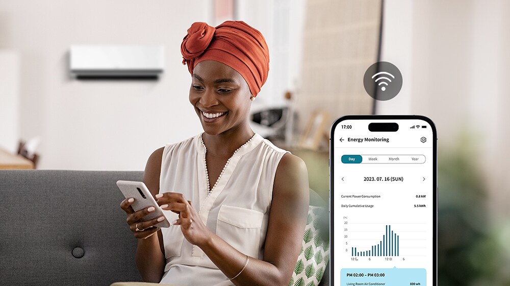 Une femme appréciant le flux d’air frais du climatiseur vérifie la consommation énergétique du climatiseur avec l’écran de l’appli ThinQ™.	