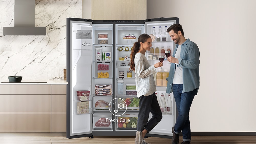 deux personnes debout devant un réfrigérateur 2 portes LG grand ouvert.