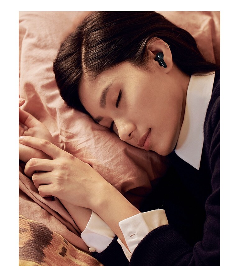 Une personne allongée sur un lit dort paisiblement, avec les écouteurs T60 aux oreilles.