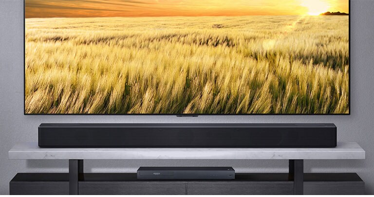 Côté avant de la barre de son sur l’étagère connectée au téléviseur et au lecteur Blu-Ray