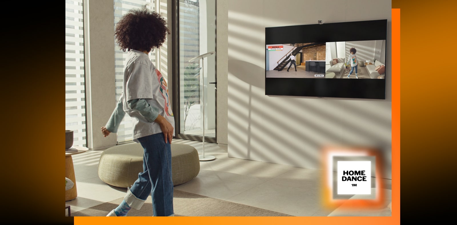 Une femme se tient debout au milieu du salon, danse et regarde la télévision en même temps. Le téléviseur montre une scène de didacticiel de danse sur la gauche et reflète une femme qui danse sur le côté droit de l’image. Le logo « 1million home dance » est visible dans le coin inférieur droit.
