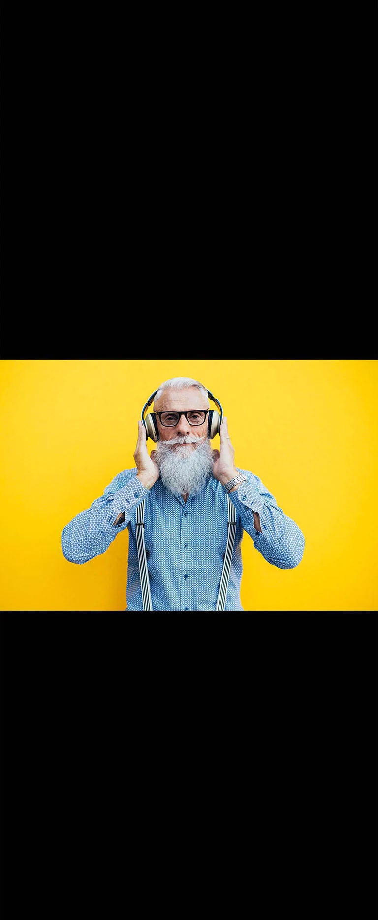 Un grand-père se tient devant un mur jaune – portant un casque.