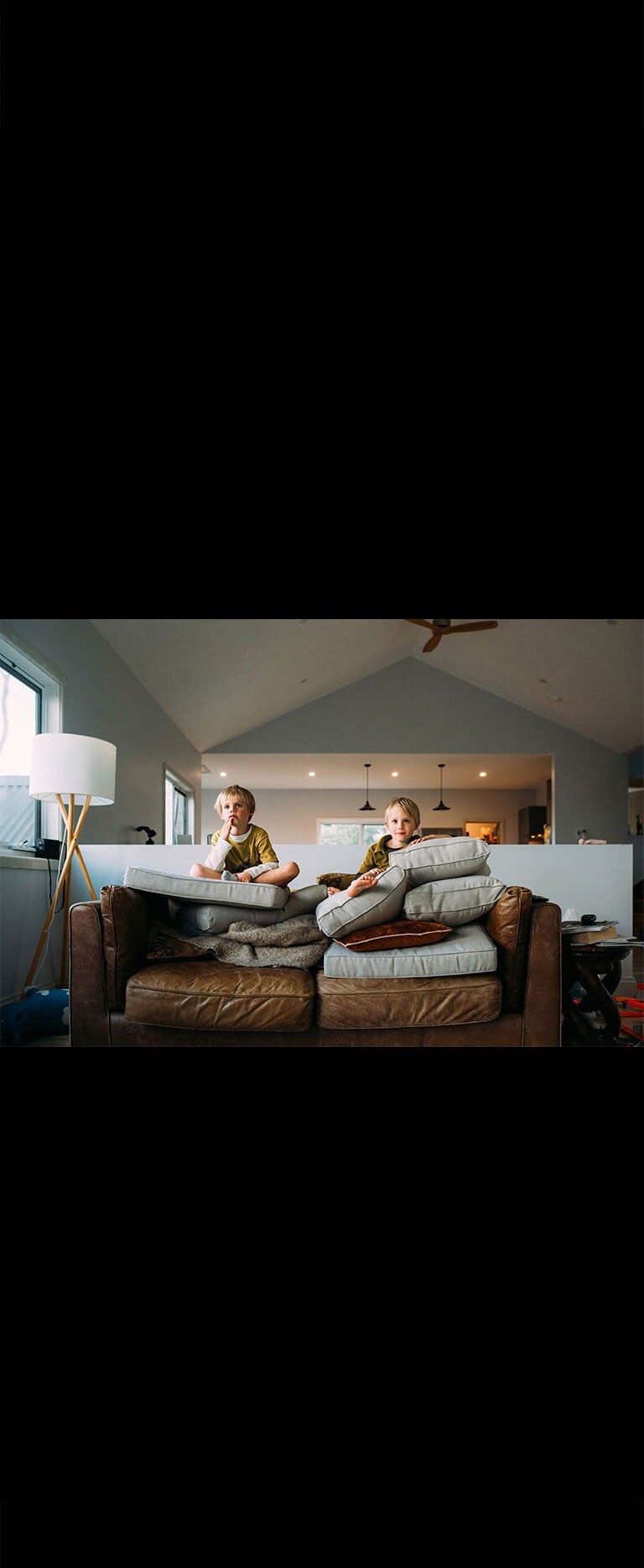 Deux jumeaux regardent quelque chose assis sur un canapé.