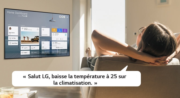 Une femme sur un canapé demandant au téléviseur de baisser la température avec l’écran d’accueil sur l’écran du téléviseur