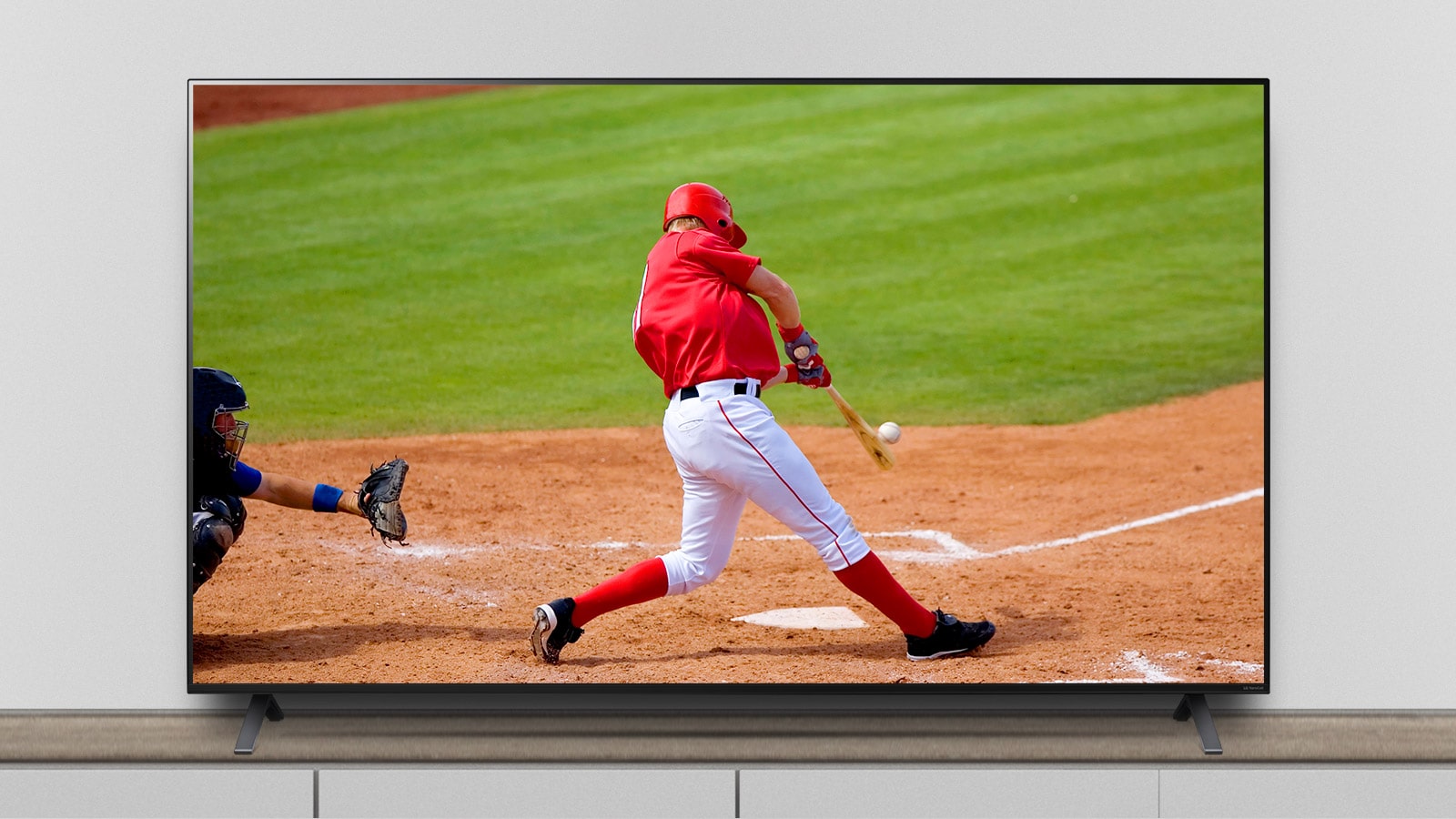 Le téléviseur est sur socle et l’écran affiche un match de baseball.