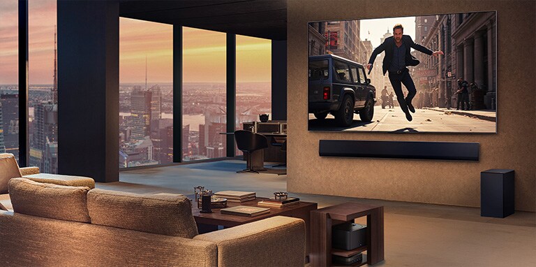 Salon élégant haut de gamme dans un appartement en hauteur. La TV LG True Wireless et la LG Soundbar sont fixées au mur. Un film est diffusé sur l’écran de TV. Aucun câble n’est visible. Le boîtier Zero Connect est caché sous une table d’appoint. 