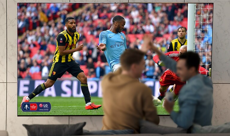 Les gens regardent un match de sport à la télévision dans le salon avec une télévision à écran ultra large