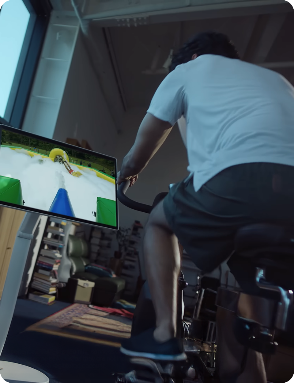 A man riding an indoor bike while looking at an LG 360 monitor.