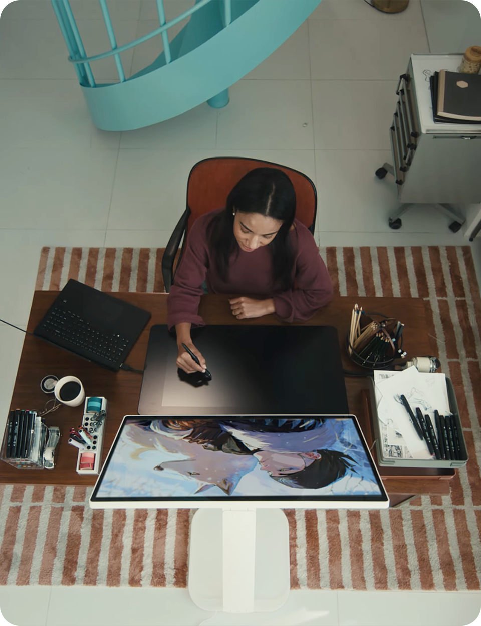 A designer drawing on a tablet while looking at an LG 360 monitor.