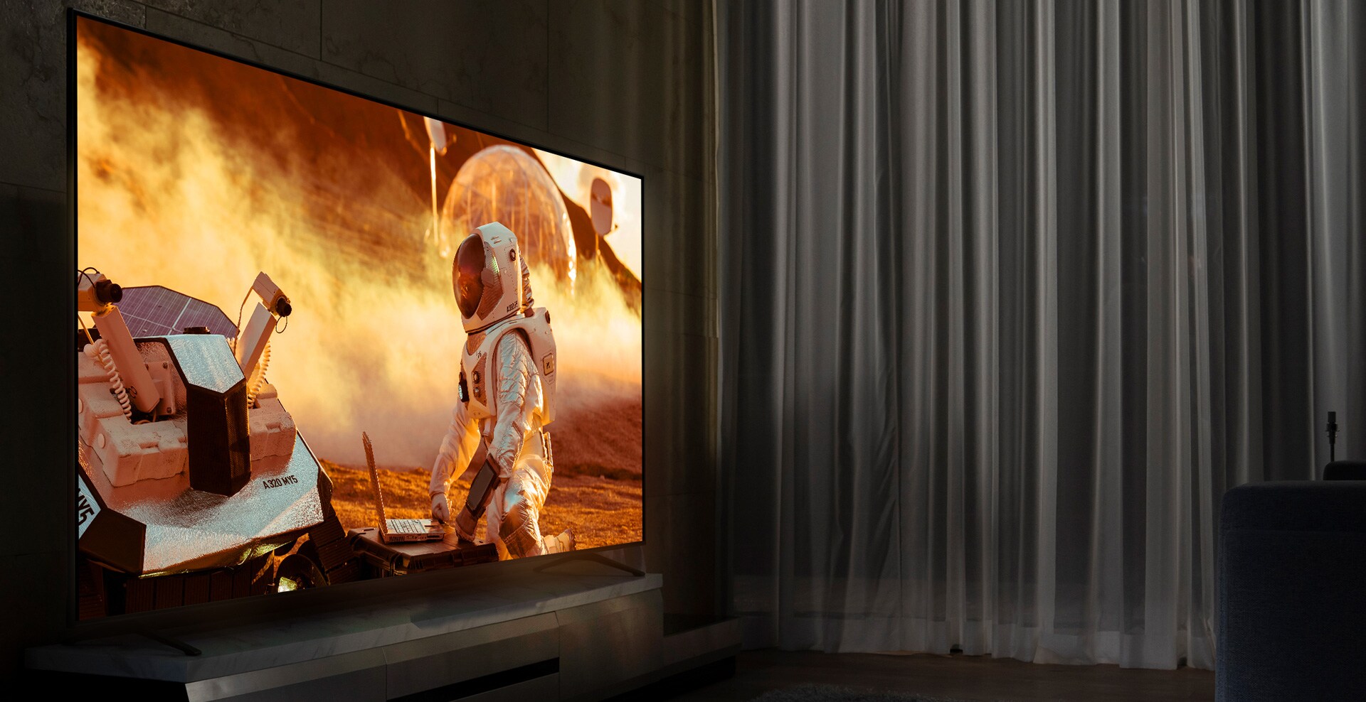 Téléviseur NanoCell dans un salon plongé dans la pénombre. Scène de film diffusée sur l’écran. La technologie NanoCell est illustrée par une amélioration de l’image en dessous du téléviseur.