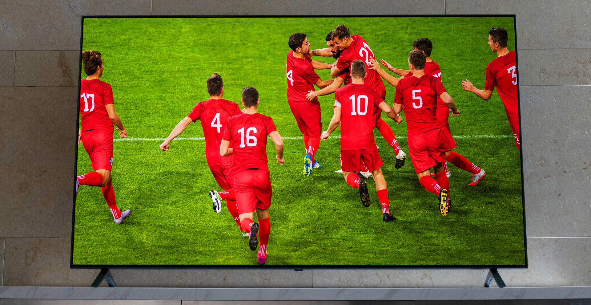 Un téléviseur NanoCell est posé sur un meubl télé. Des joueurs de football se congratulent.