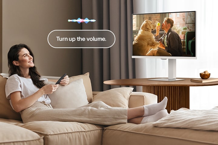 Една жена увеличава силата на звука на LG Smart Monitor с помощта на дистанционното управление Magic Remote.