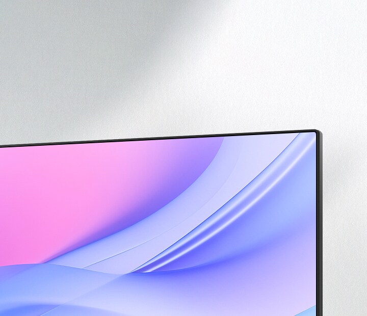 Изглед отблизо под ъгъл на горния десен ъгъл на монитор, показващ ултратънката му рамка и безрамковия дизайн на екрана. Дисплеят се отличава с плавен розово-син градиент, подчертаващ изчистена и модерна естетика, идеална за минималистични конфигурации.	