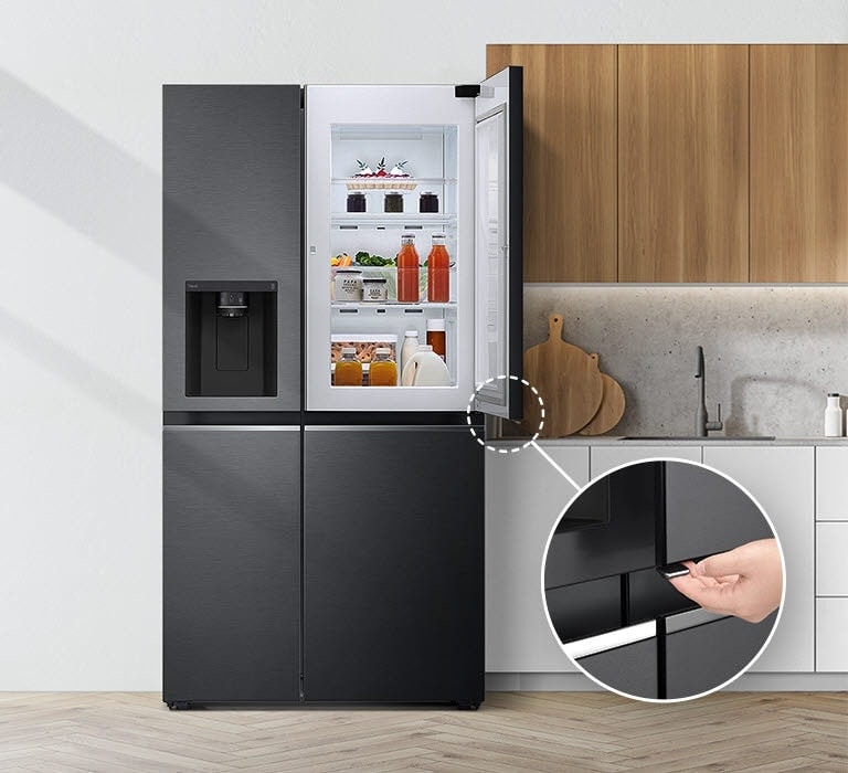 Изглед отпред на хладилник, монтиран в кухня. Горната дясна врата е отворена и има кръг и линия, водещи към по-голям кръг, който показва увеличен изглед на бутона в долния ляв ъгъл на отворената врата, която има скрит бутон за отваряне.