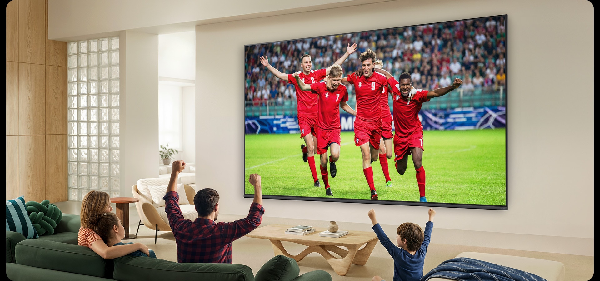 LG QNED evo AI QNED80 Mini LED Ultra Big TV е монтиран на стената в светла всекидневна и показва футболен мач с ярки цветове.