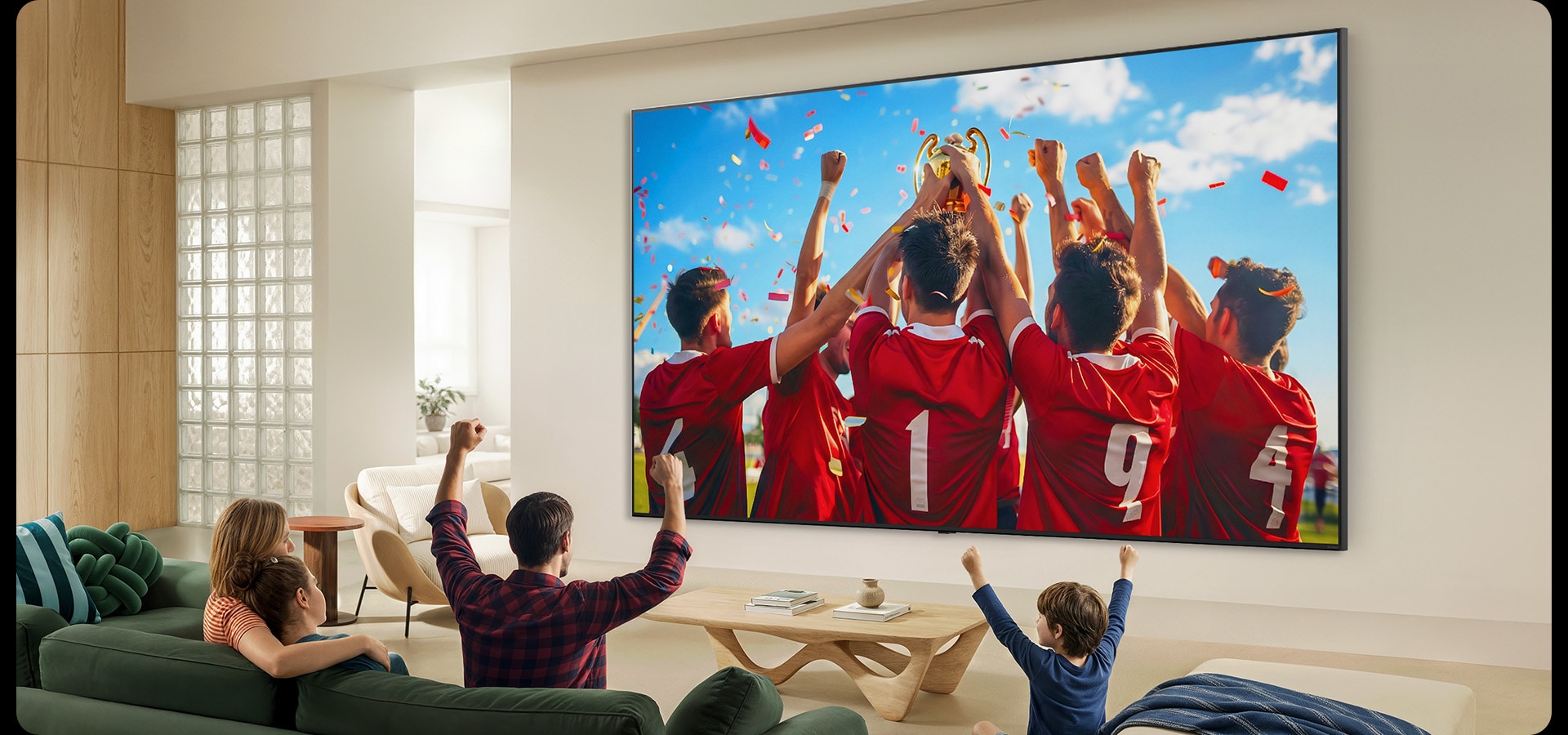 LG QNED evo AI QNED85 Mini LED Ultra Big TV е монтиран на стената в хола и излъчва празненствата по повод спортна победа.