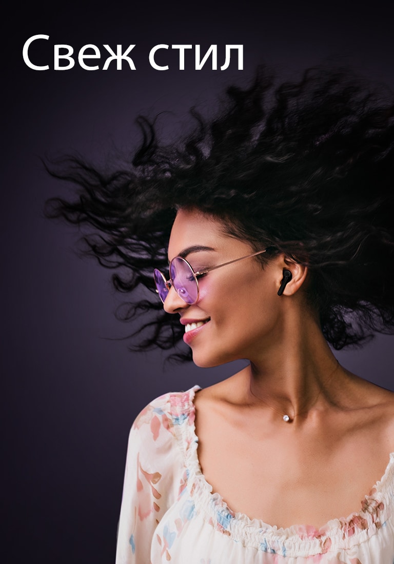 Жена се усмихва, докато слуша музика с TONE Free.