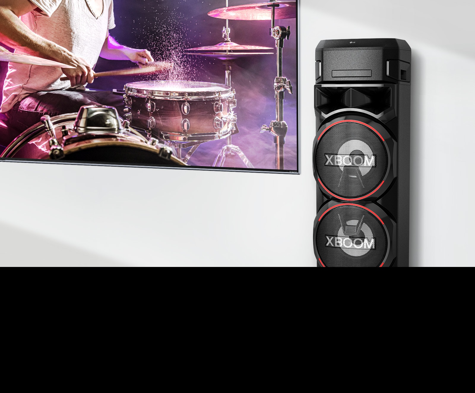 На стената е окачен телевизор, а вдясно от него има LG XBOOM.