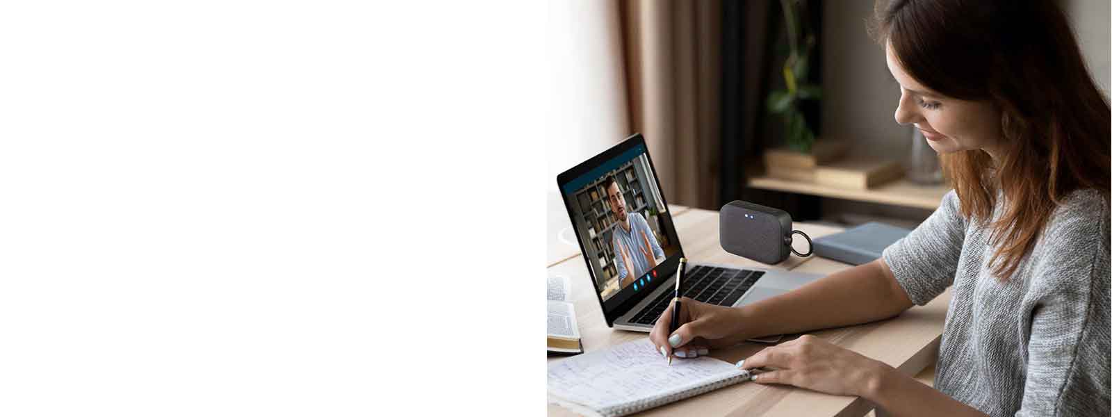 Жена е във видеоконферентен разговор с колега, като същевременно си води бележки. На бюро е поставен високоговорител XBOOM Go PN1.