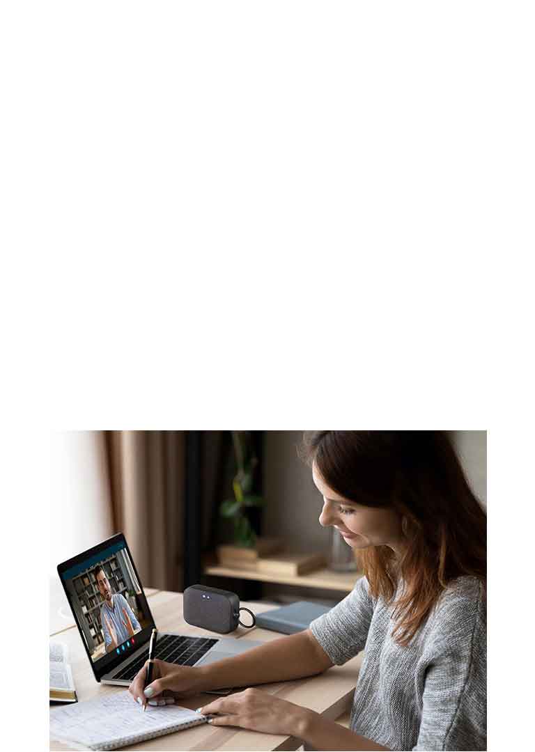 Жена е във видеоконферентен разговор с колега, като същевременно си води бележки. На бюро е поставен високоговорител XBOOM Go PN1.