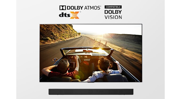 Телевизор и саундбар заедно, в пълен ракурс. На екрана на телевизора се вижда двойка, която пътува към залеза в автомобил с отворен покрив.