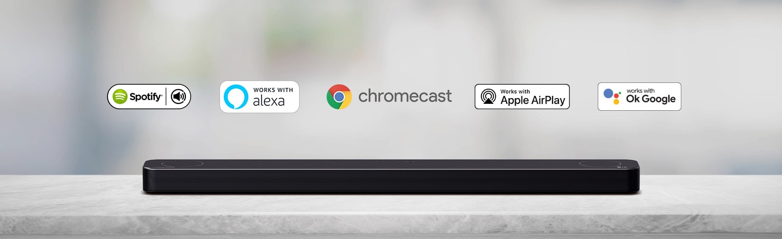 На сив рафт е поставен саундбар и има лога на AI платформата по реда на Spotify, Alexa, Chromecast, Apple Airplay и OK Google от ляво надясно.