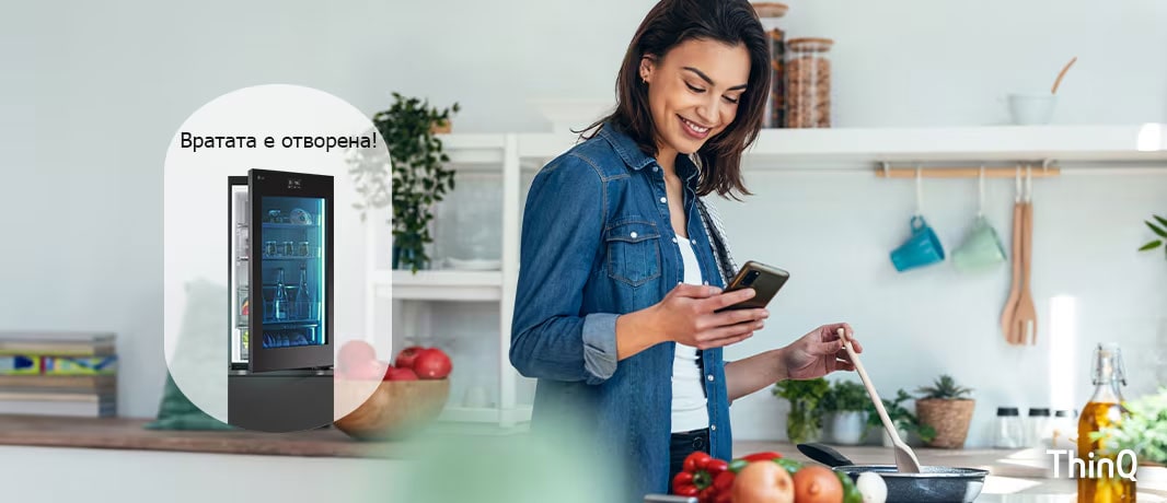 Изображение на жена, която получава известие на смартфона си от приложението LG ThinQ за това, че вратата на хладилника е оставена отворена, докато тя готви.