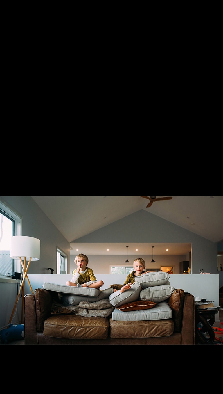 Две момчета близнаци гледат нещо, седнали на диван.