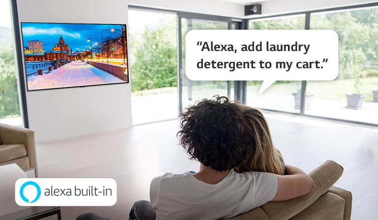 Двойка седи на диван и моли Amazon Alexa да добави прах за пране в количката за пазаруване