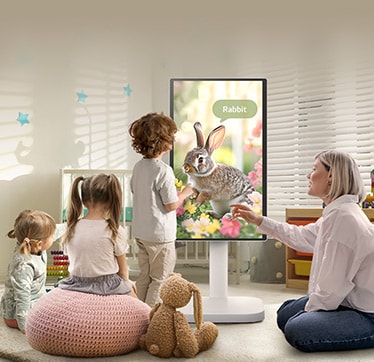 Тази снимка показва жена и три деца, играещи с LG Smart Monitor Swing.