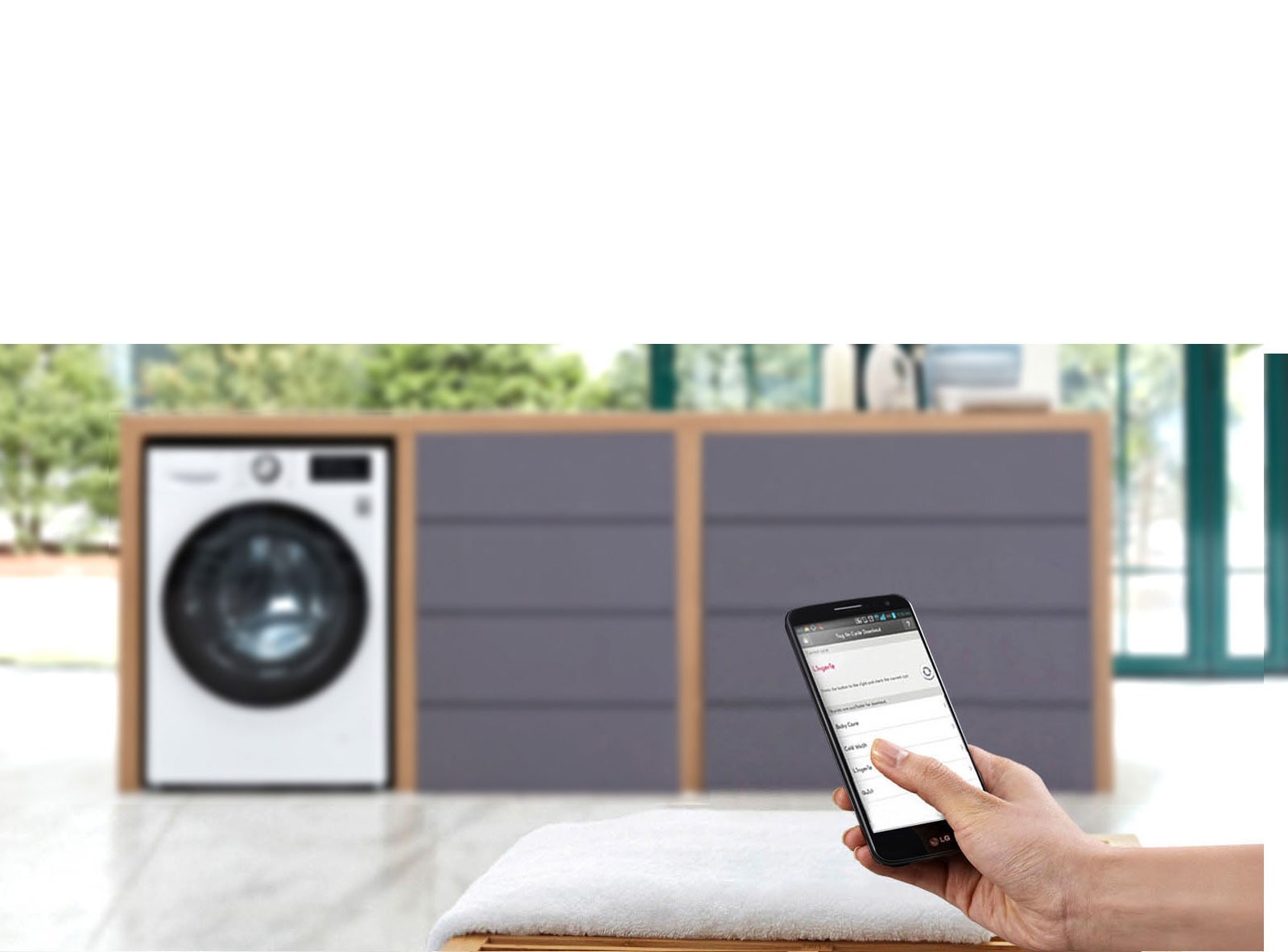 Човек управлява пералня със сушилня LG чрез приложението ThinQ на смартфон, като уредът е на заден план.
