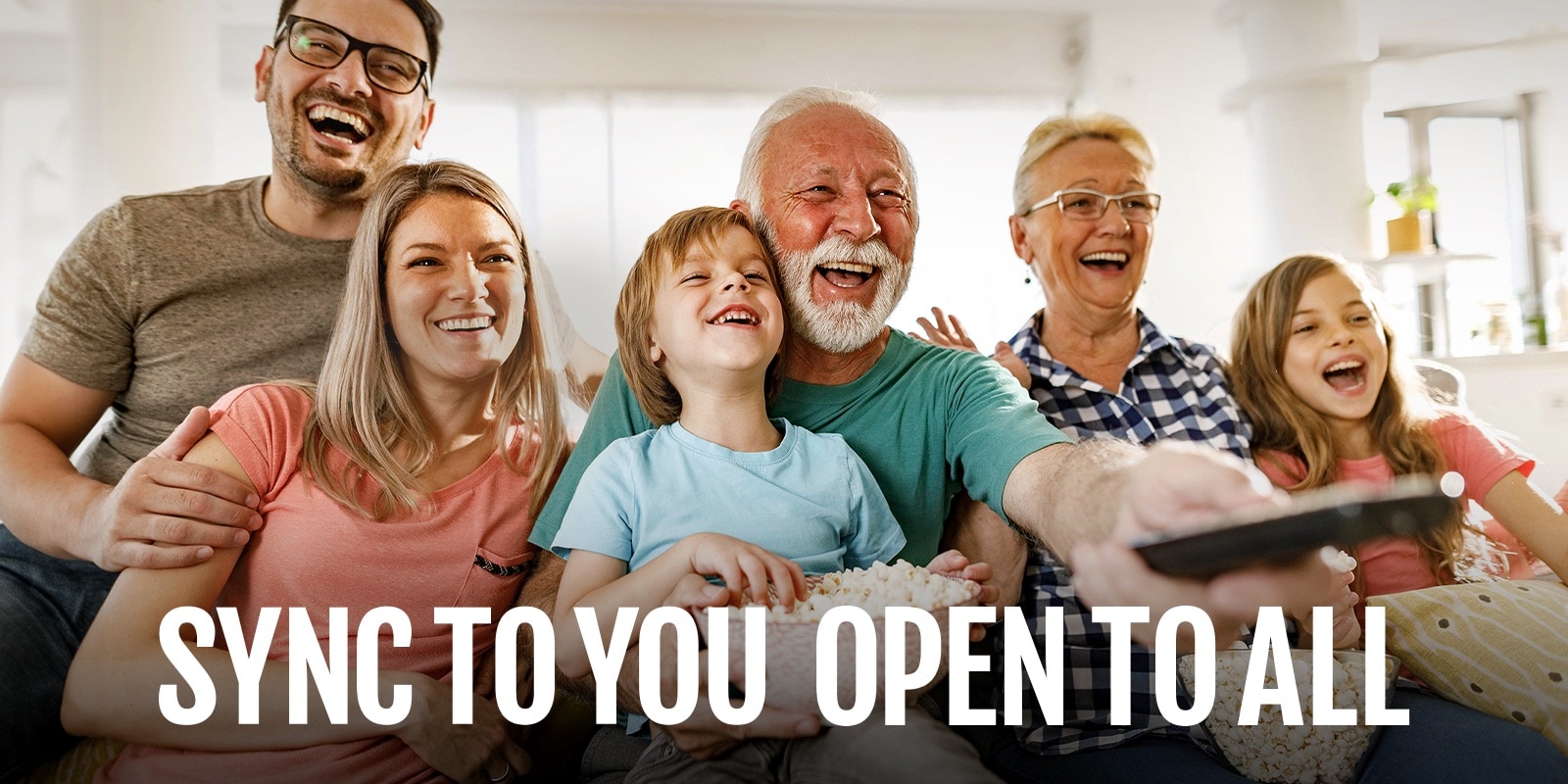 Едно семейство седи и се смее, докато дядото насочва дистанционното настрани.