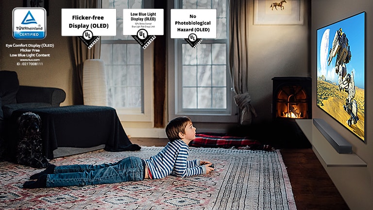 Дете, което лежи на пода, държи джойстик и играе игра на екрана на телевизор