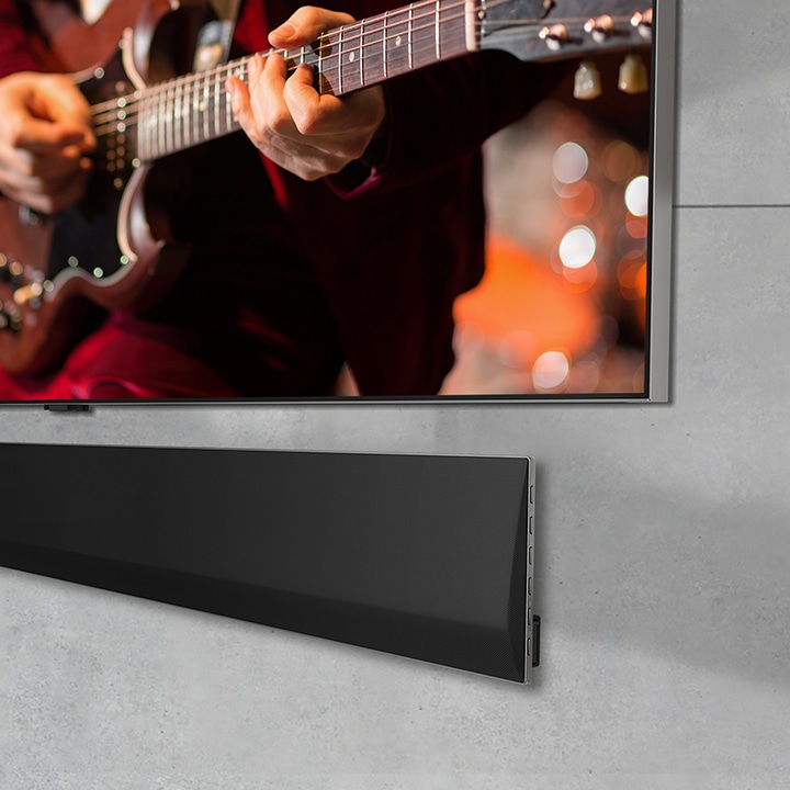 Близък план под ъгъл на долната част на LG OLED TV и LG Soundbar, монтирани на стена.