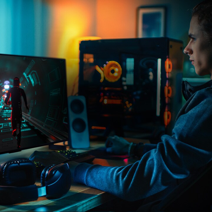 Човек играе научнофантастична игра на бюрото си на малък телевизор LG OLED