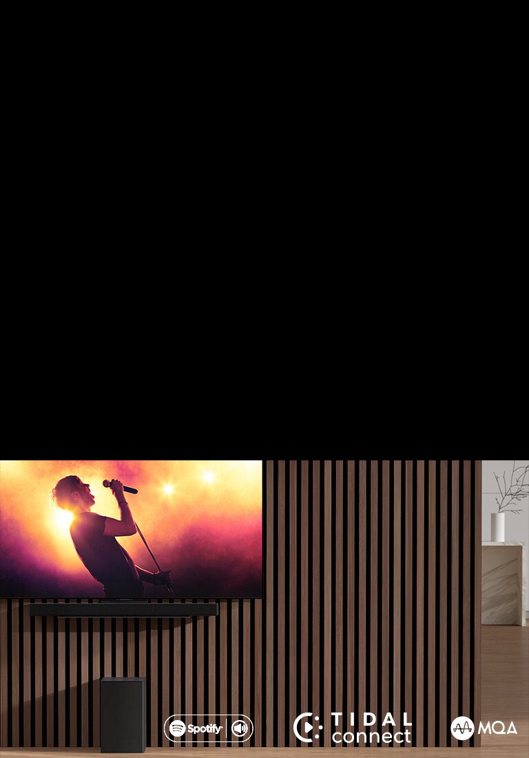 El LG OLED C está en la pared y, debajo, la barra de sonido LG SC9S con un soporte exclusivo. El subwoofer está debajo. El televisor muestra una escena de un concierto.
