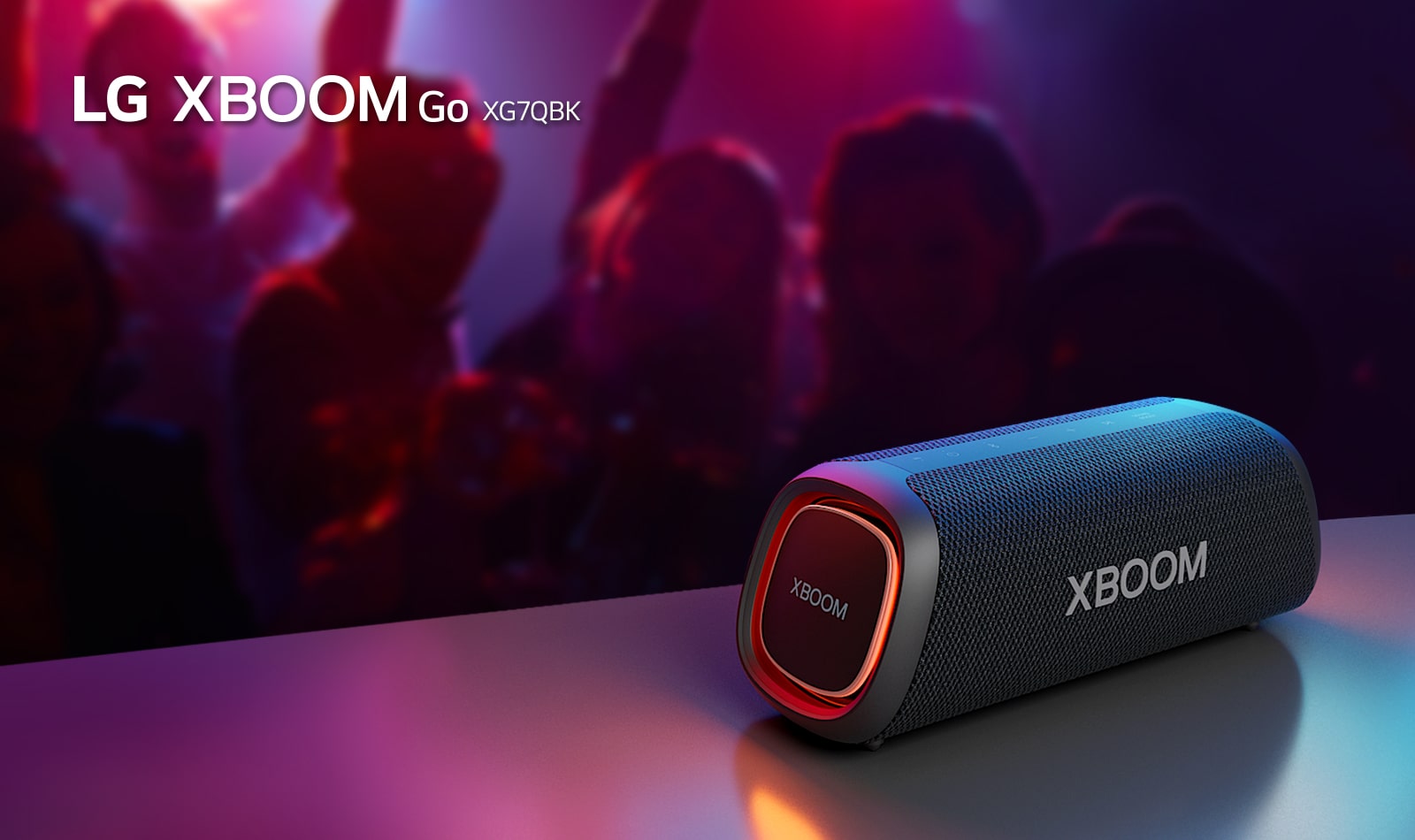 LG XBOOM Go XG7 está colocado sobre la mesa de metal con una luz naranja encendida. Detrás de la mesa, la gente disfruta de la música.