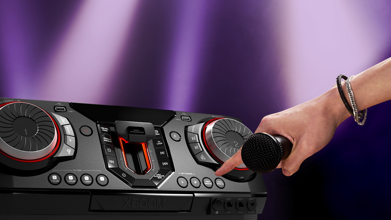 La imagen muestra un fondo borroso con focos de color violeta. En el lado izquierdo de la imagen, hay un primer plano de la vista lateral del receptor, con una mano sosteniendo un micrófono. El dedo índice se extiende para presionar el botón de karaoke.