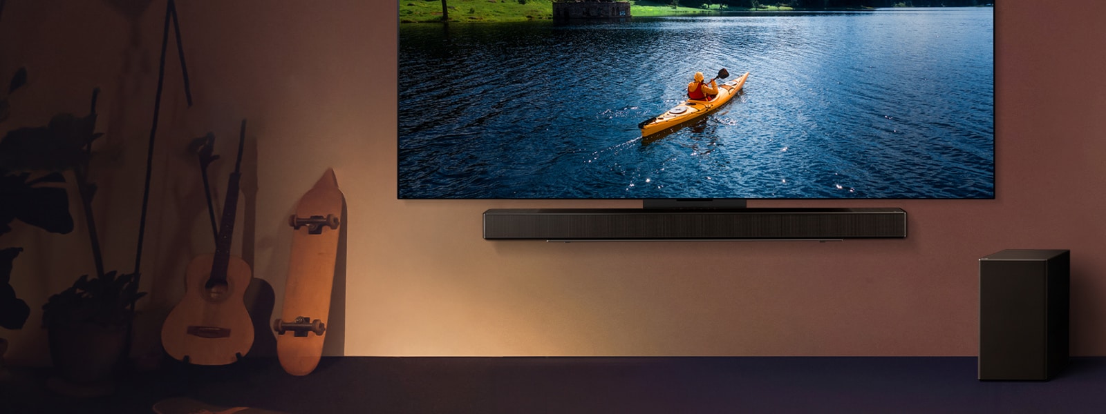 LG TV y Soundbar montadas en una pared y una bocina subgrave en el piso a la derecha. En la TV se muestra a una persona en un kayak en un lago y sombras suaves caen en cascada sobre la pared.