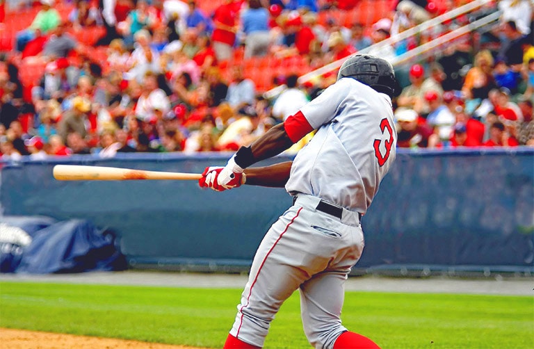 Un jugador de béisbol batea durante un partido frente al público en un estadio.