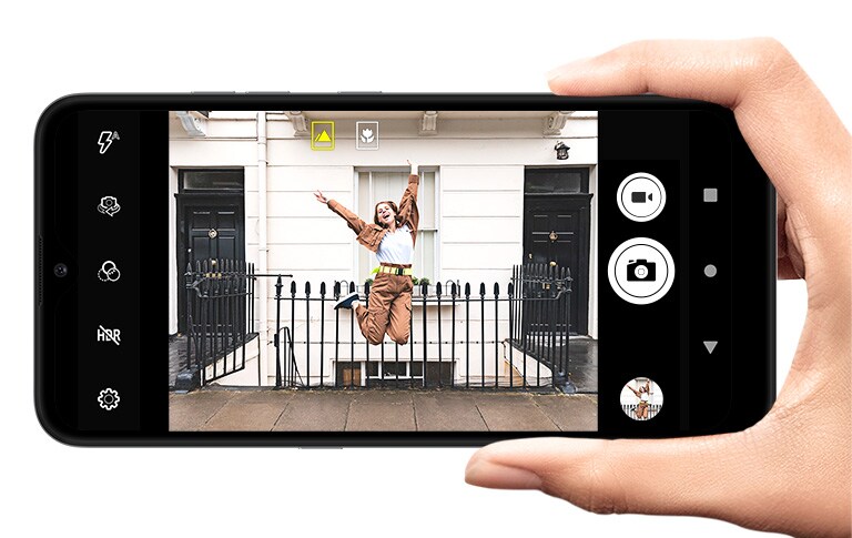 Smartphone taking a photo of a woman who poses and jumps on the street