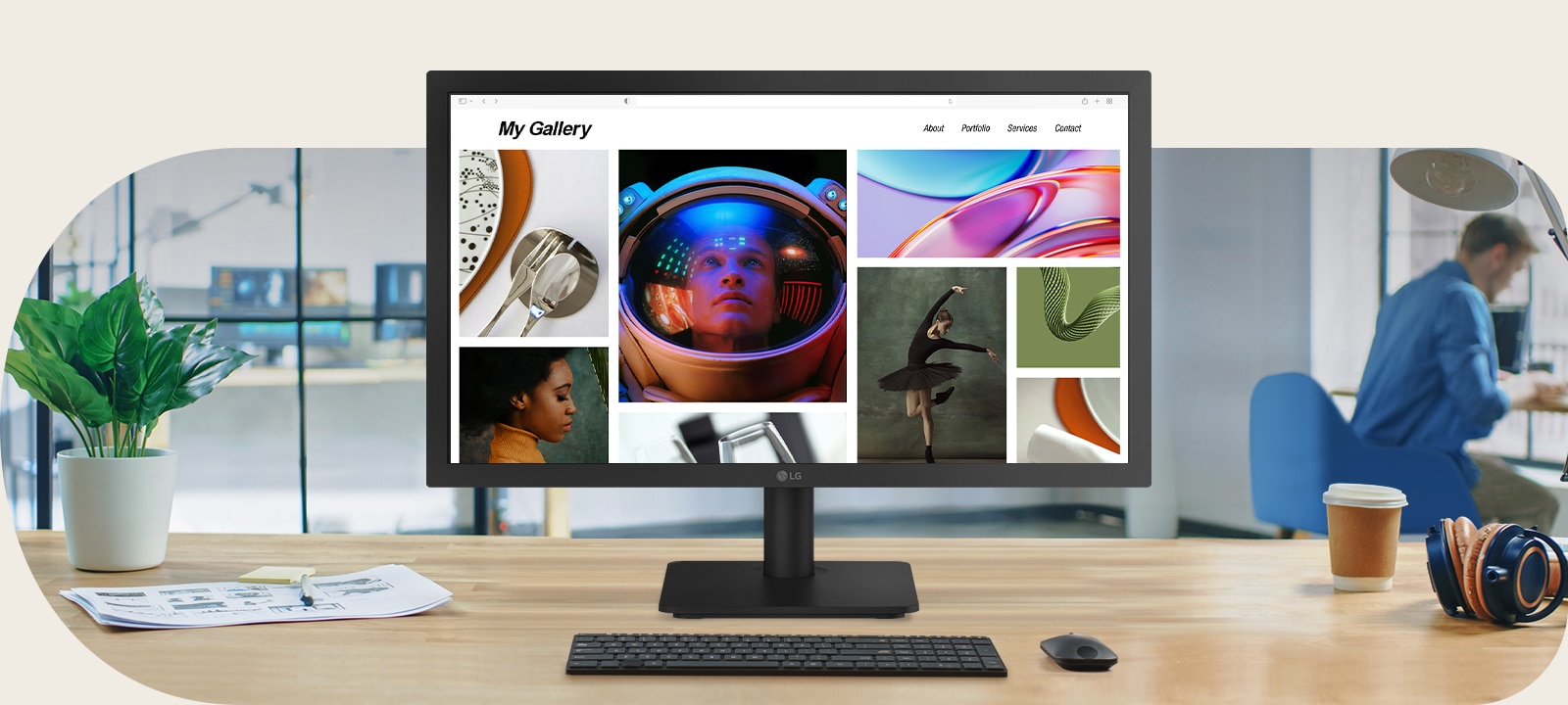 Monitor LG Full HD de 22 pulgadas en un moderno escritorio de oficina que muestra una colorida página web de galería de fotos, rodeado por un teclado, mouse, taza de café y auriculares en un espacio de trabajo luminoso.