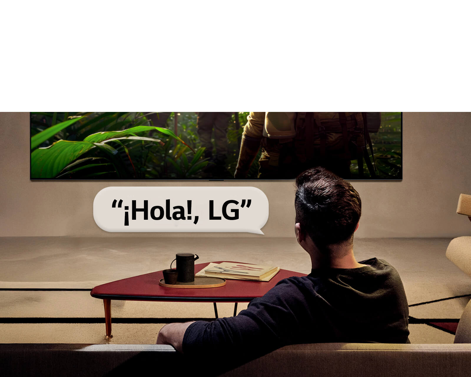 LG OLED evo AI C6 con Reconocimiento de Voz de Campo Lejano se activa mediante un comando de voz cuando una persona sentada en una habitación dice “Hola, LG” hacia el televisor, indicando una interacción por voz manos libres dentro de la interfaz del televisor.