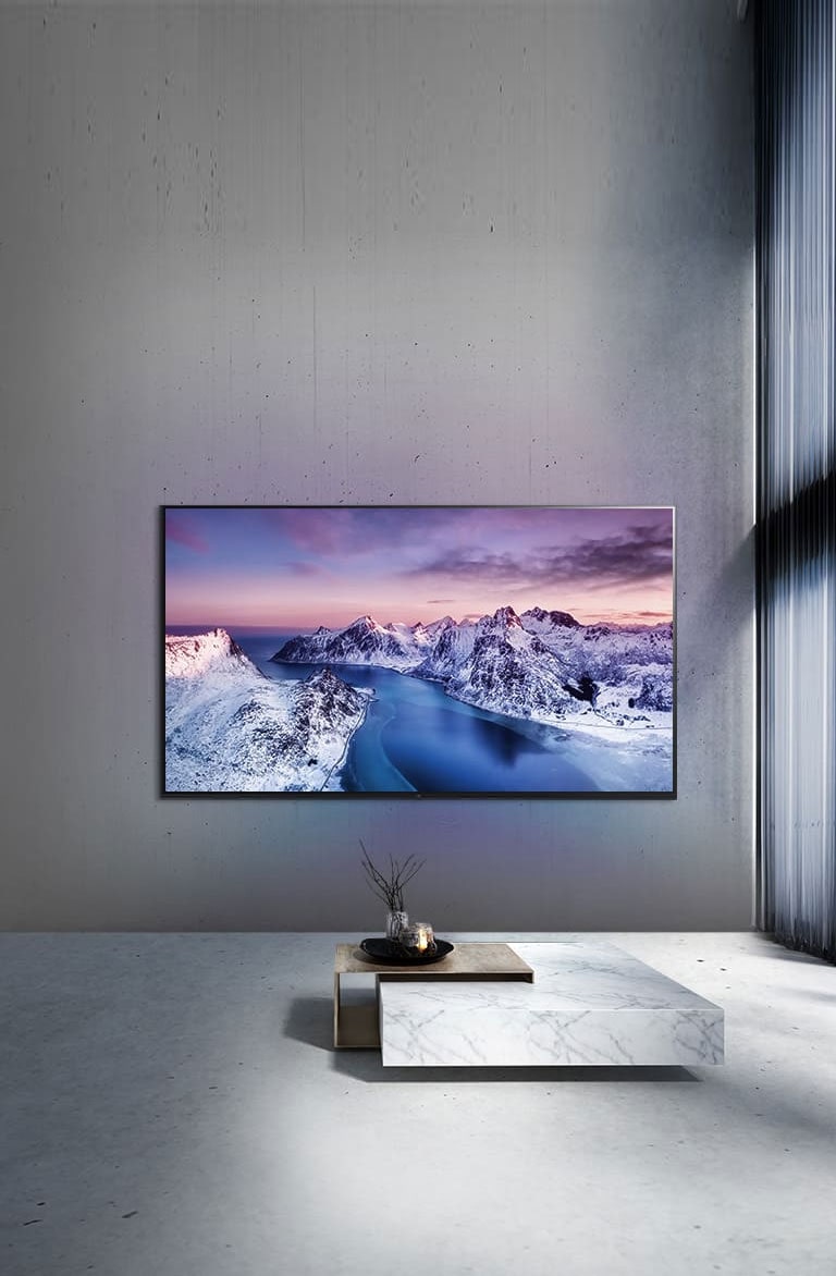 Un televisor UHD montado en la pared detrás de una mesa con ambientación de estilo zen.