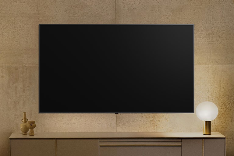 Una LG TV wall-mounted aparece apagada, pero la función Always Ready se enciende. Muestra información y luego recorre diferentes obras de arte.