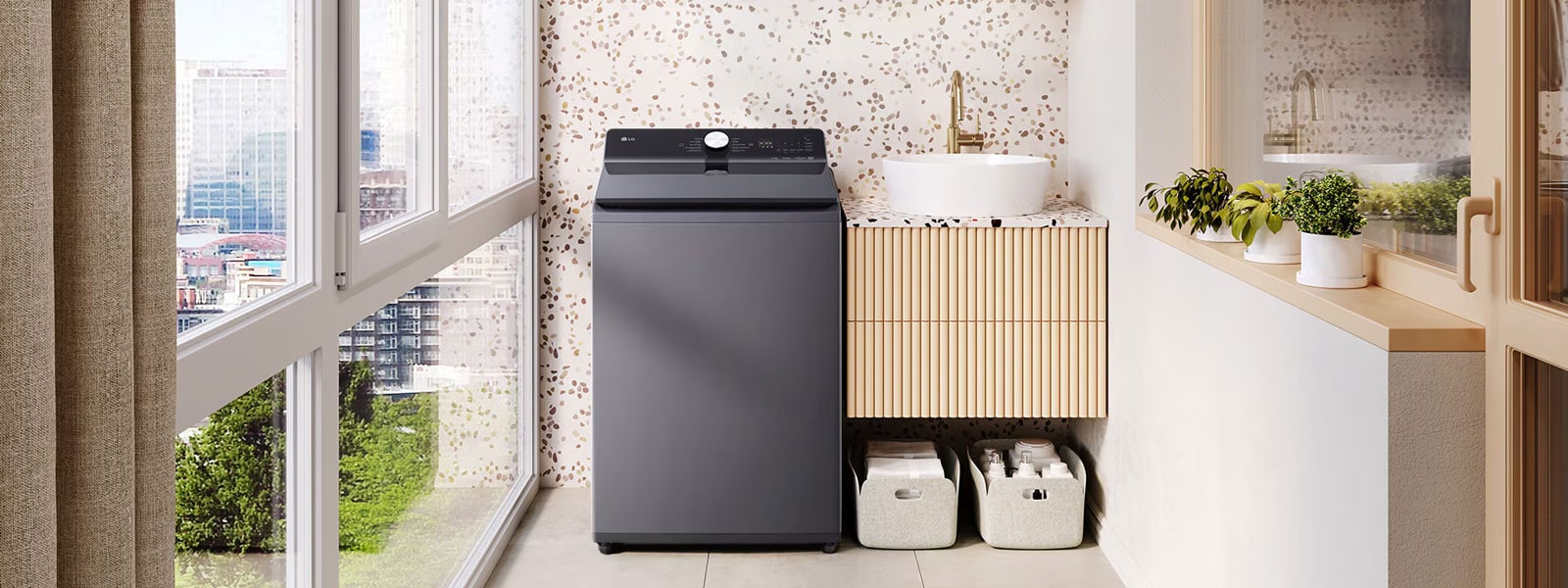 Lavadora de carga superior LG gris oscuro en un lavadero luminoso con plantas, cestas de almacenamiento y vista de la ciudad a través de las ventanas