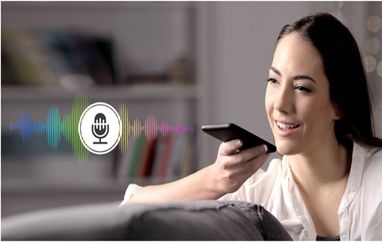 Una mujer controla la TV hablándole a un control remoto con reconocimiento de voz.