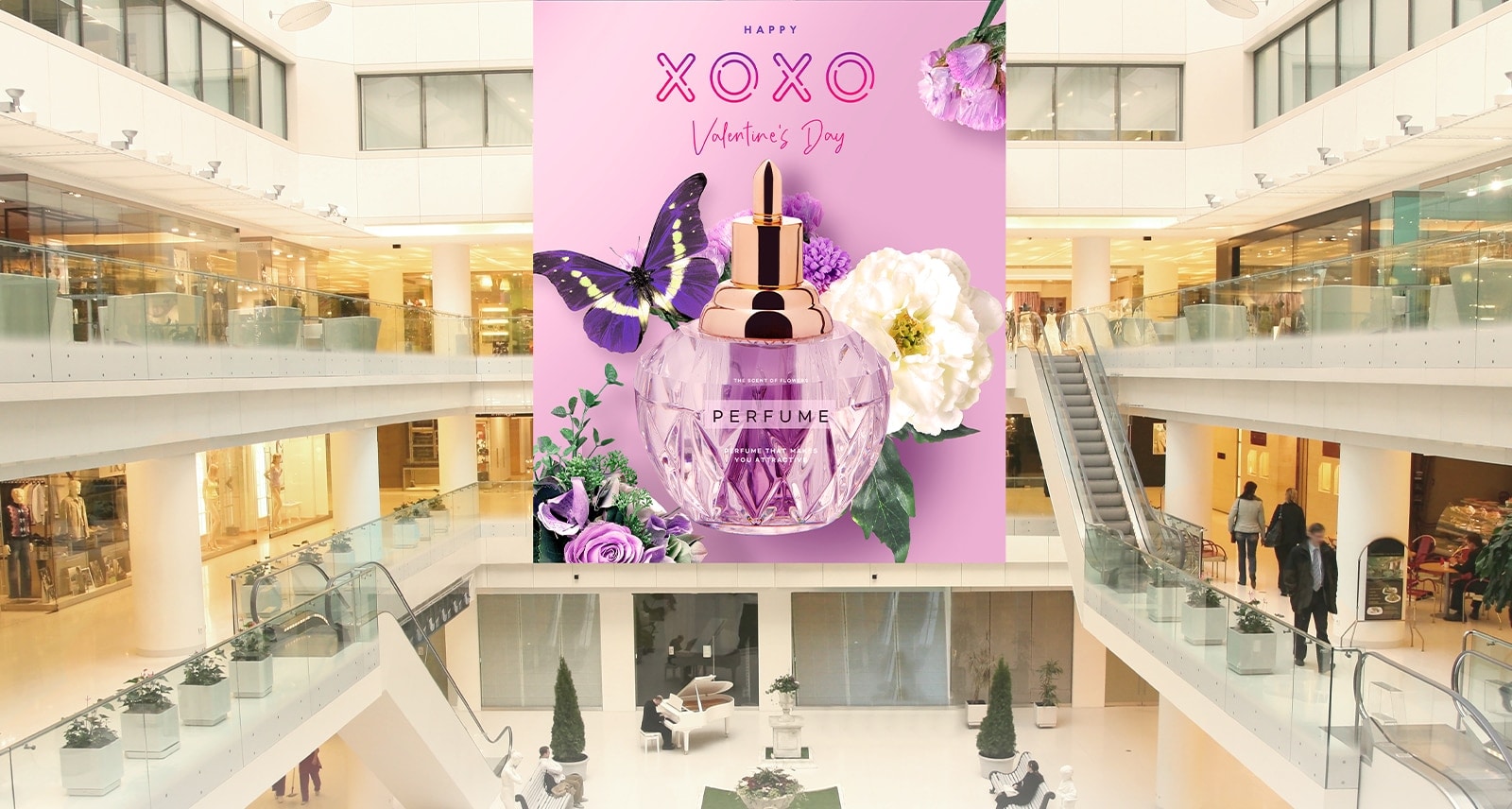 Hay grandes pantallas LED instaladas en tres pisos de un gran centro comercial, que muestran de forma destacada anuncios de perfumes.